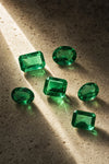 Loose Colombian emeralds on ivory travertine