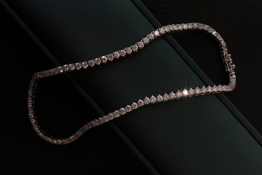 A tennis necklace with round-cut lab-grown diamonds, displayed against a dark background.